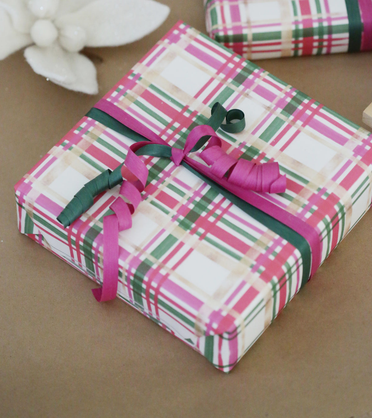 Christmas present wrapped in golden, white and pink wrapping paper with green and pink bows